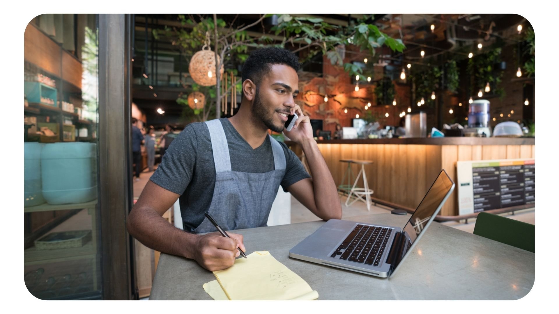 Restaurant manager working on phone, laptop and pen and paper