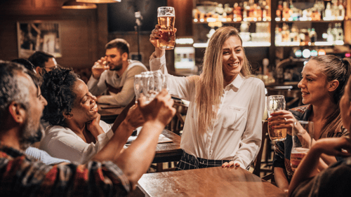 Cheerful pub patrons smiling and raising glasses