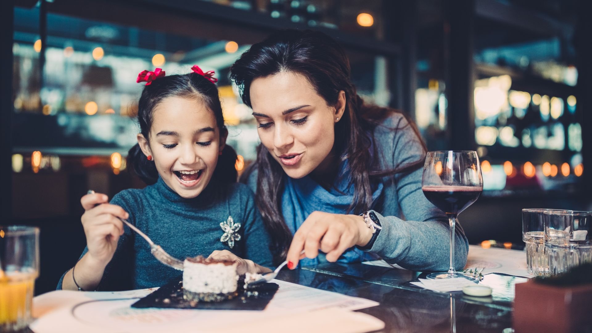 Mother and daughter eating a dessert in restaurant