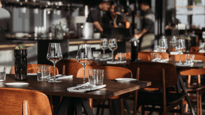 Photo of restaurant tables with staff meeting in the background