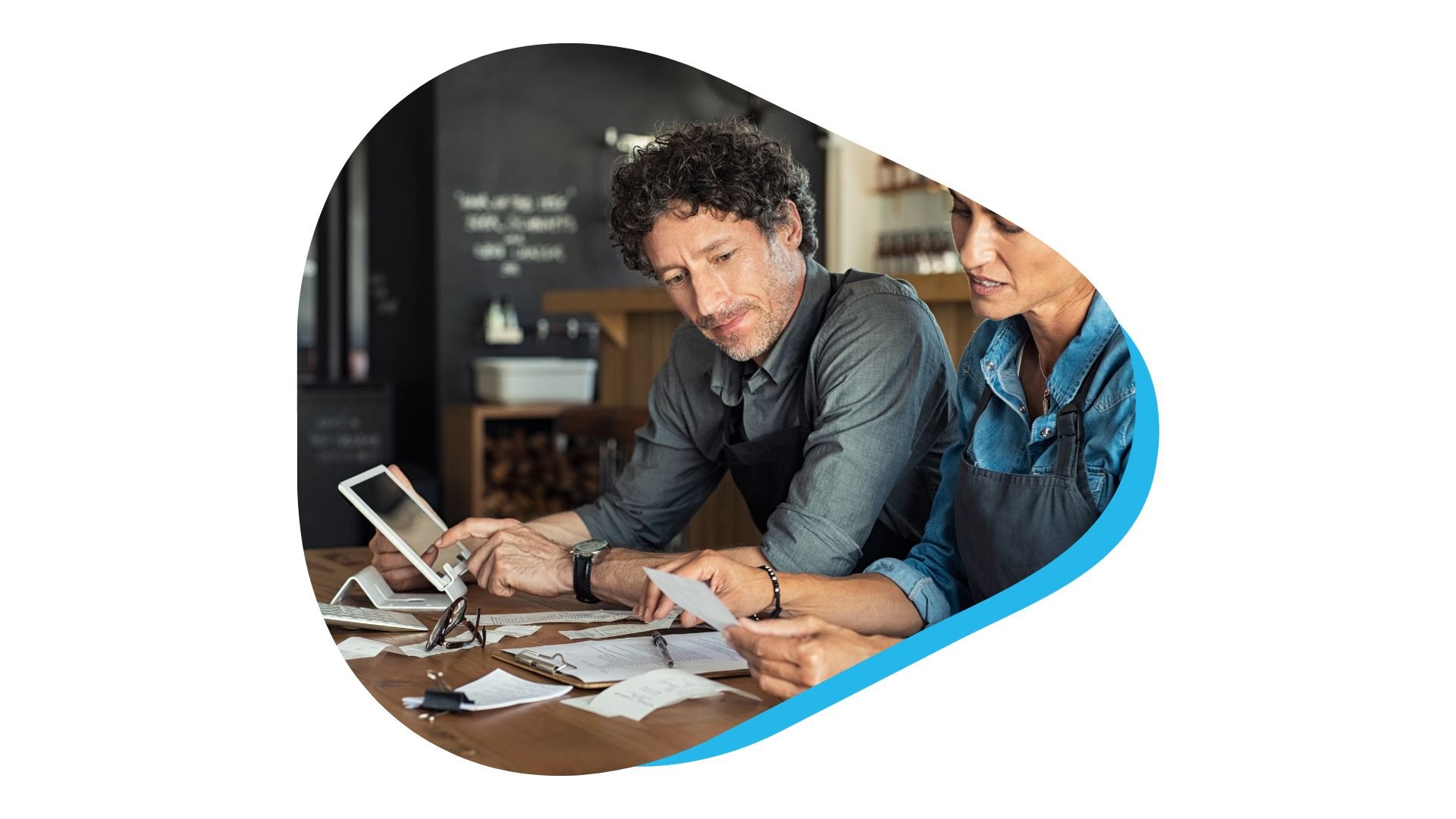 Two restaurant managers in a meeting working on tablet devices and paper notes