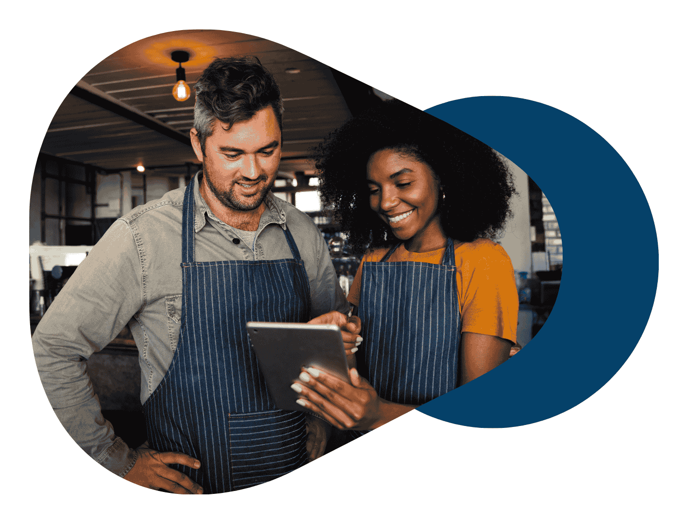 Two restaurant staff in aprons looking at a tablet