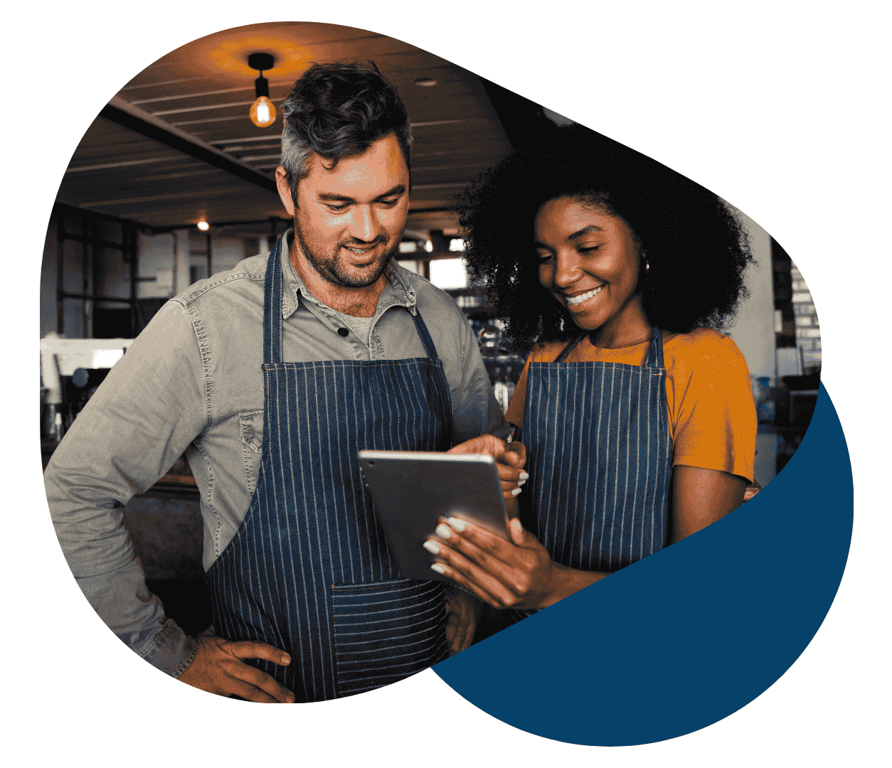 Two restaurant staff in aprons reviewing tablet